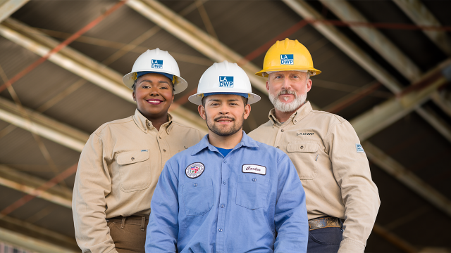 Three LADWP Employees pose for pictures, Women on left, two males on the right smiling.