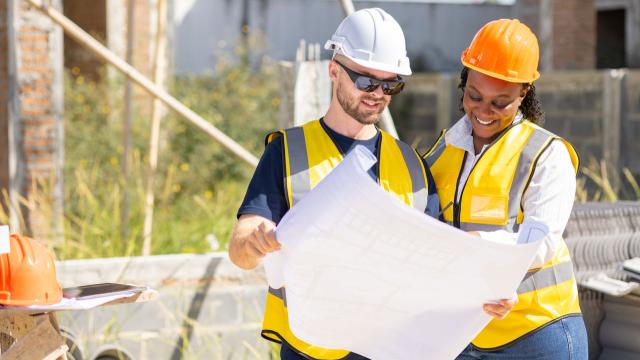Man and Women review drafting plans at construction site