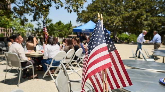 American flags with a background of people gathering in a park setting