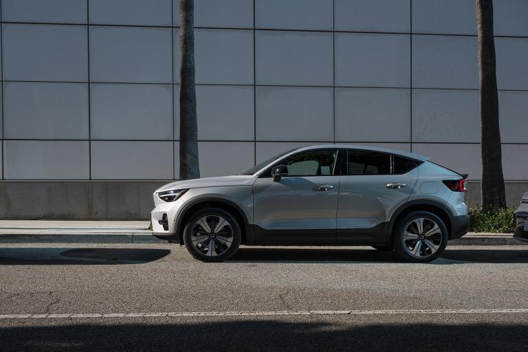 a silver EV in front of a glass building