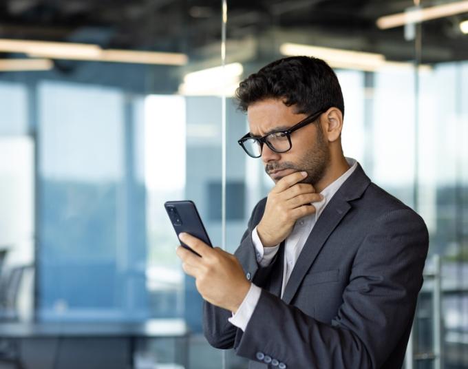 A man in a suit looks at his smartphone.