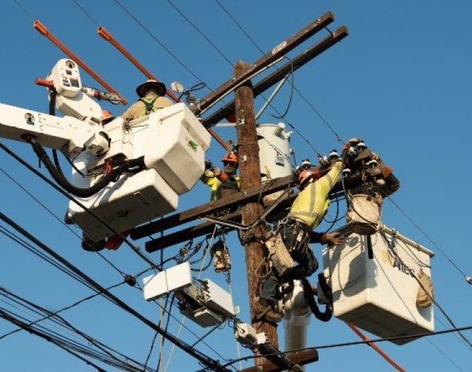 Crew lifted by bucket trucks to make repairs to a power pole.