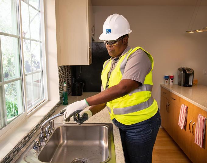 Woman installing a water aerator to a sink faucet.