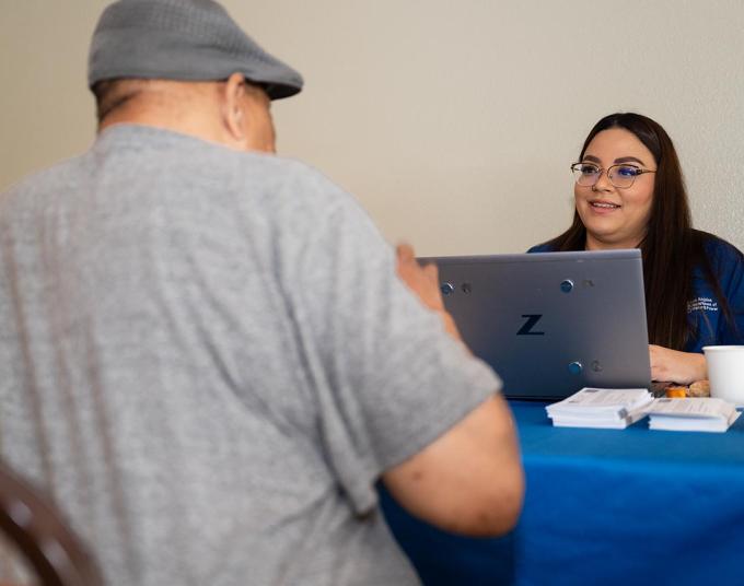 Smiling woman is sitting at a table across from a man. 