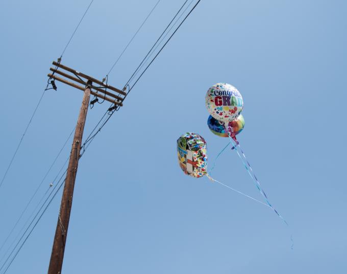 Three Mylar balloons released outdoors going towards power lines. 