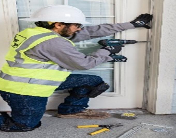 Man using a drill to install window sealing.