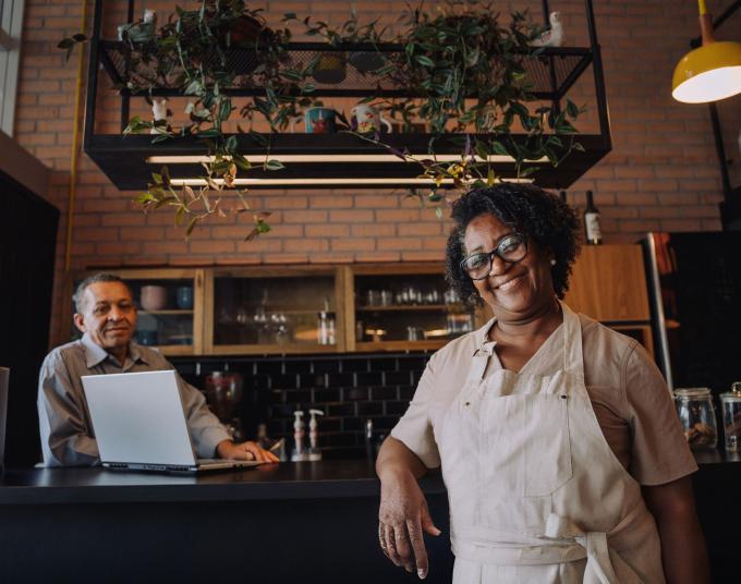 woman leaning on counter with man behind counter in their small business shop