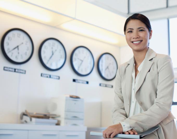 Woman in office with 4 clocks in the background