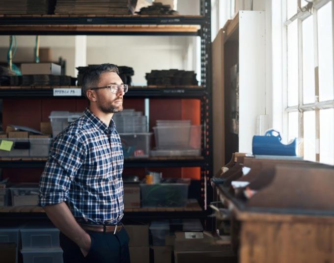 man staring out window in warehouse