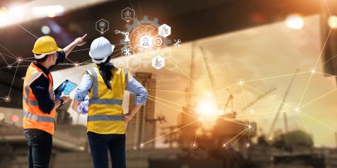 Two people in safety vests and hard hats point to a graphic representing interconnecting ideas.