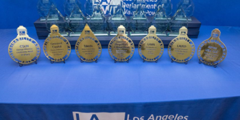 The Sustainability Awards trophies are displayed on a table with a blue tablecloth bearing the LADWP logo.
