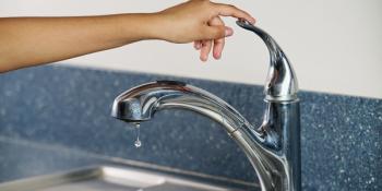 Photo of hand with finger on bathroom faucet handle